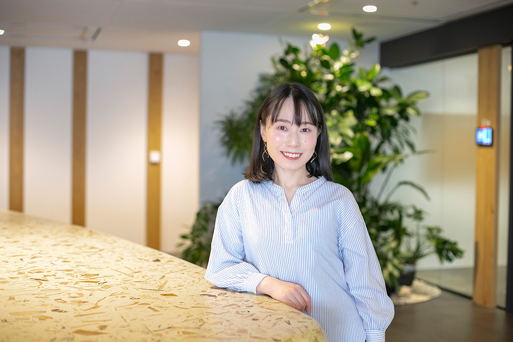 整理収納アドバイザーの松尾千尋さん。観葉植物を背に、カウンターにもたれてほほ笑むポートレート
