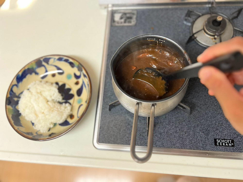 冷凍ソースを温める片手鍋とご飯の皿。焦げ付きにくい丸みのある底