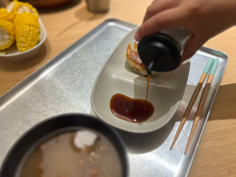 食卓で小皿にしょうゆを注ぐ様子。持ちやすいくぼみ付き