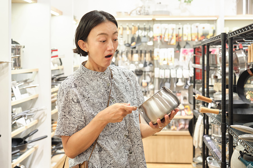 メモリ付きのステンレス製ミルクパンを手に取る本多さおりさん